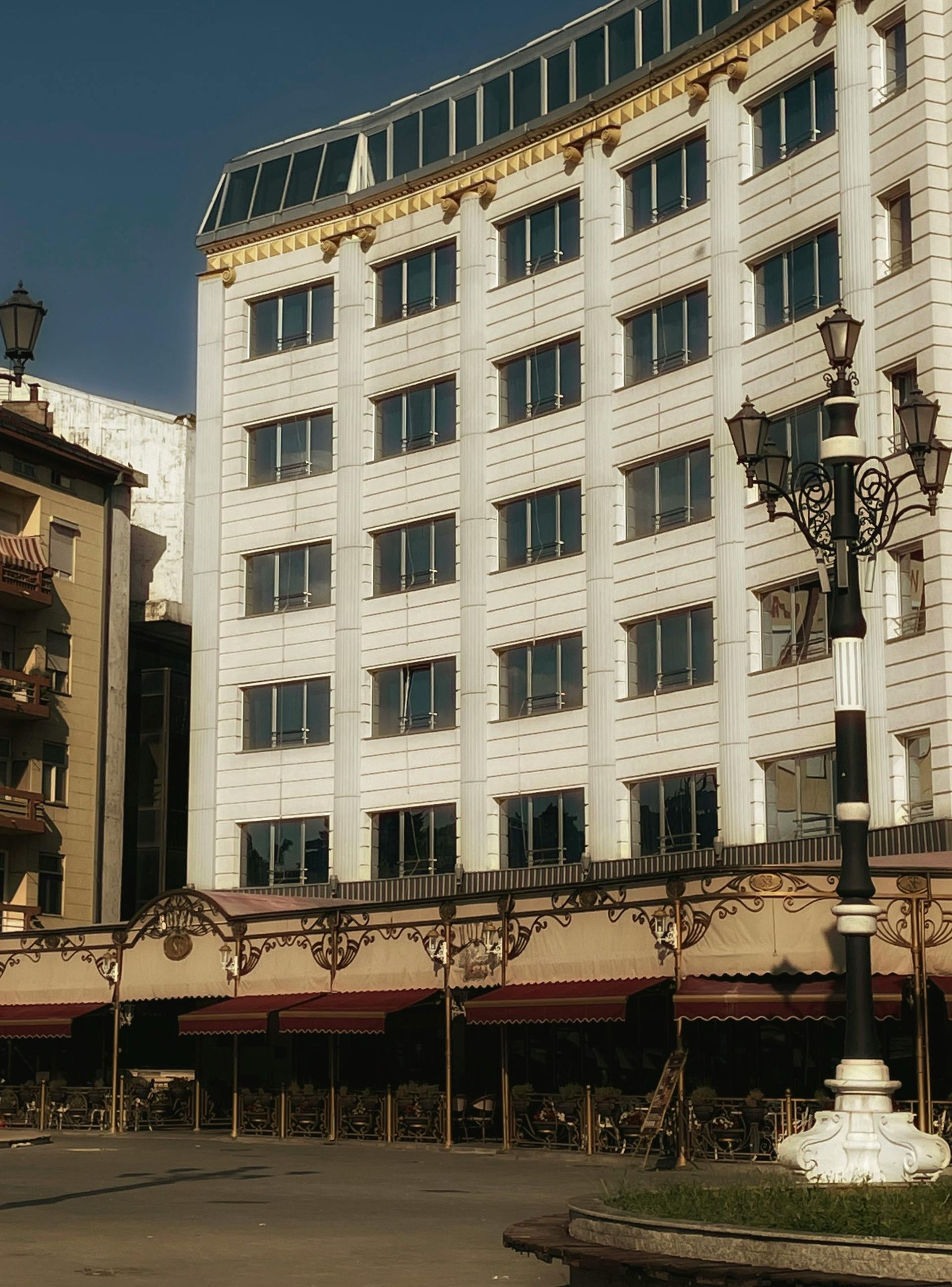 White multi-story building with awnings and ornate street lamp.