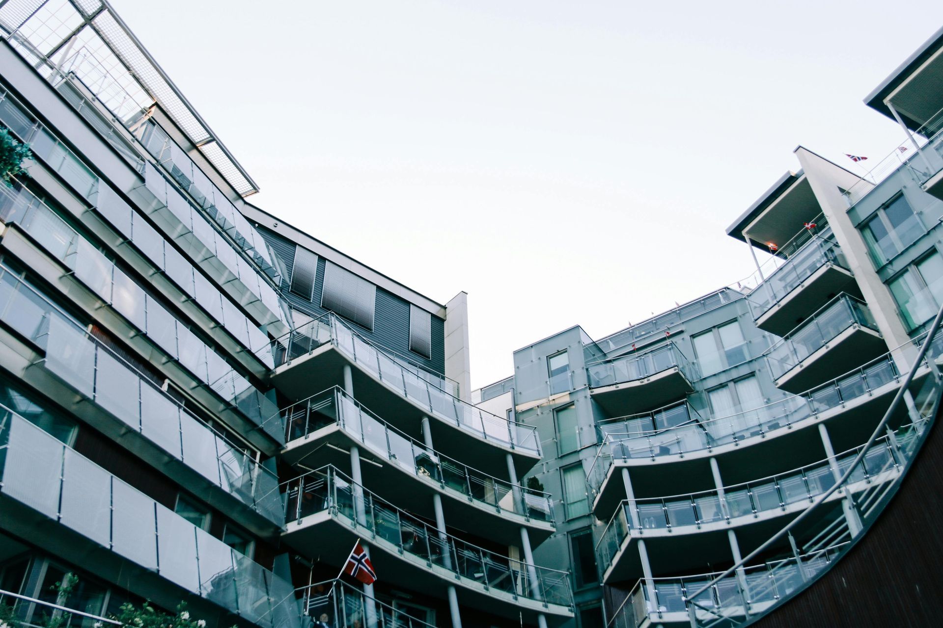 Modern apartment building with glass balconies and cloudy sky.