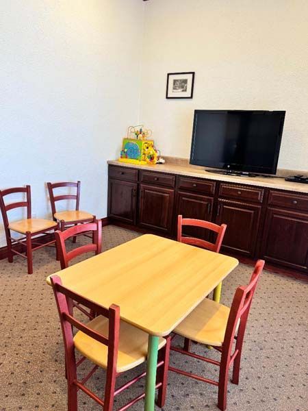 Playroom with small table and chairs, TV, and cabinets. Red and wood tones.