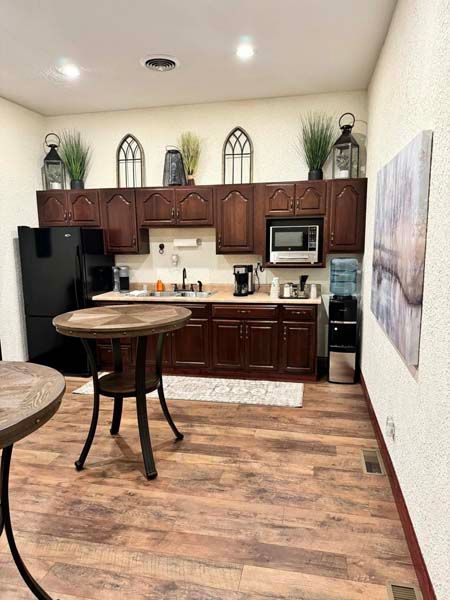 Kitchen with dark wood cabinets, black appliances, round table, and water cooler.