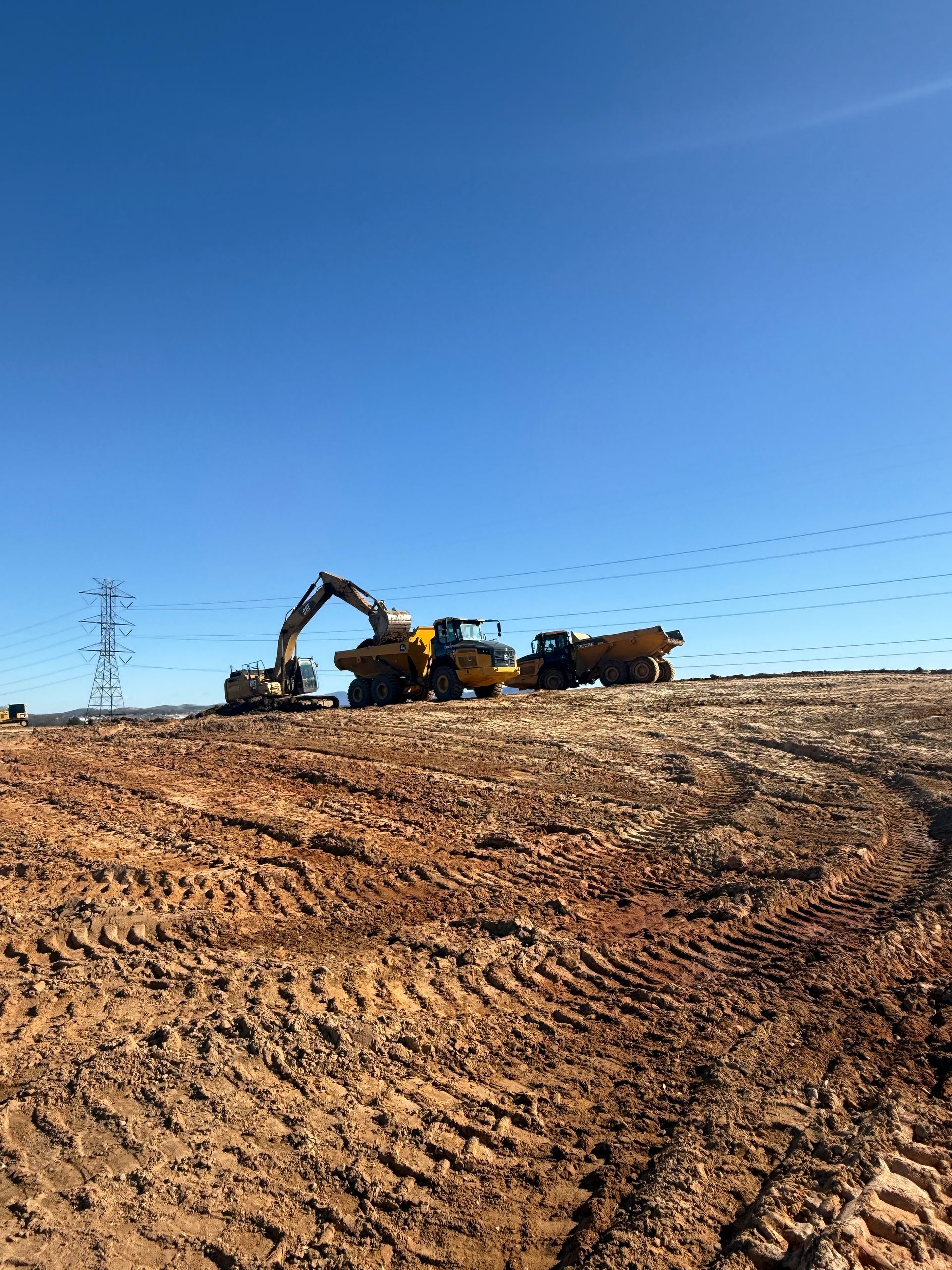 A yellow excavator is digging in a dirt field.