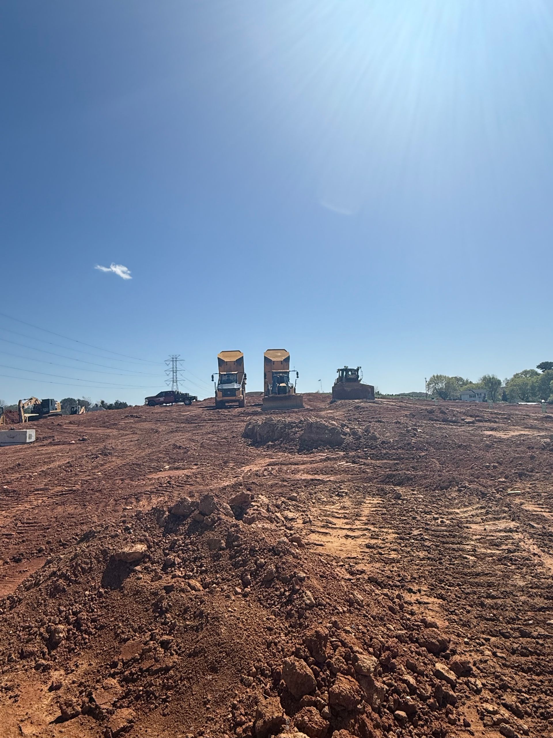 A yellow excavator is digging a hole in the dirt in the middle of a forest.
