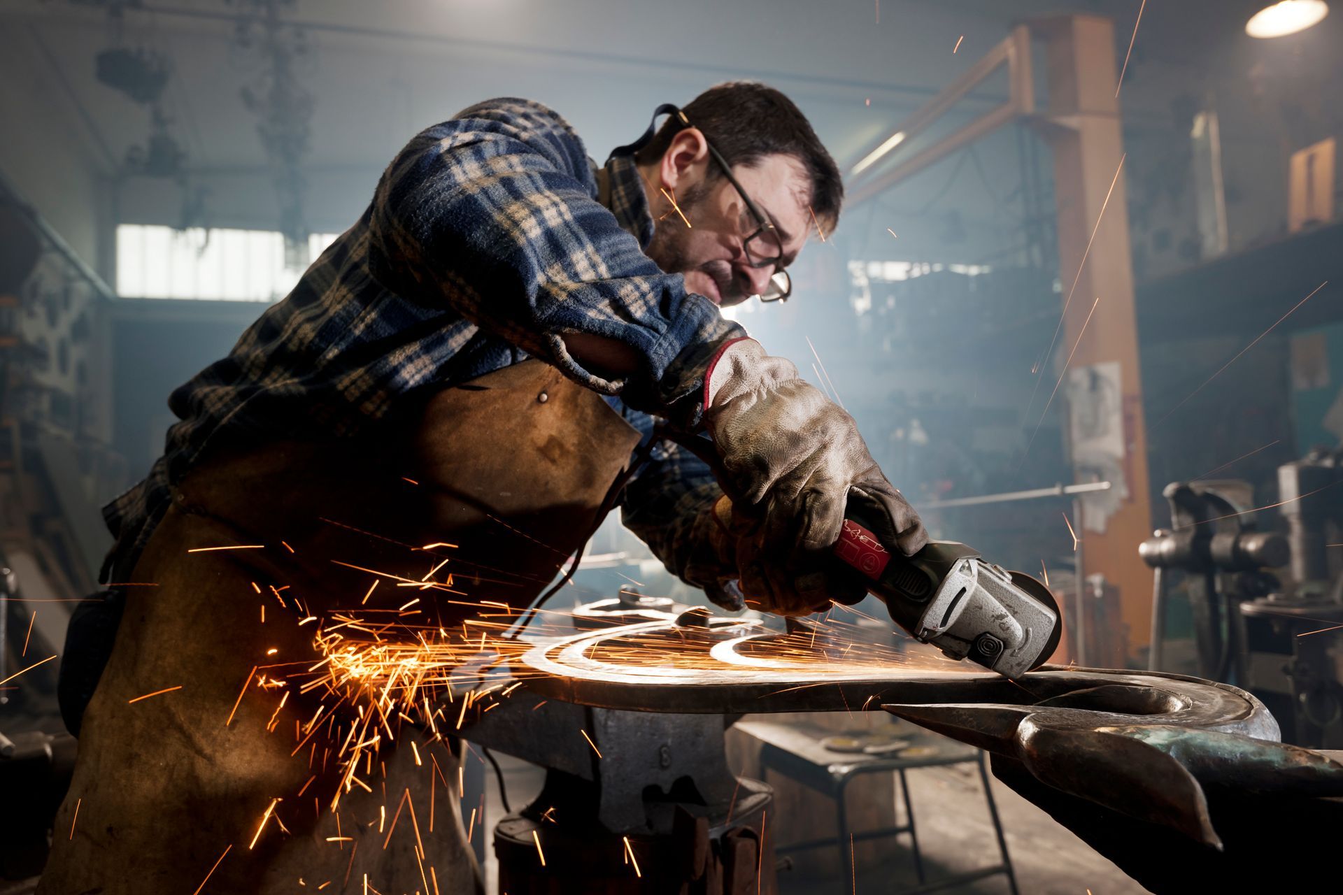 A man is grinding a piece of metal in a workshop.