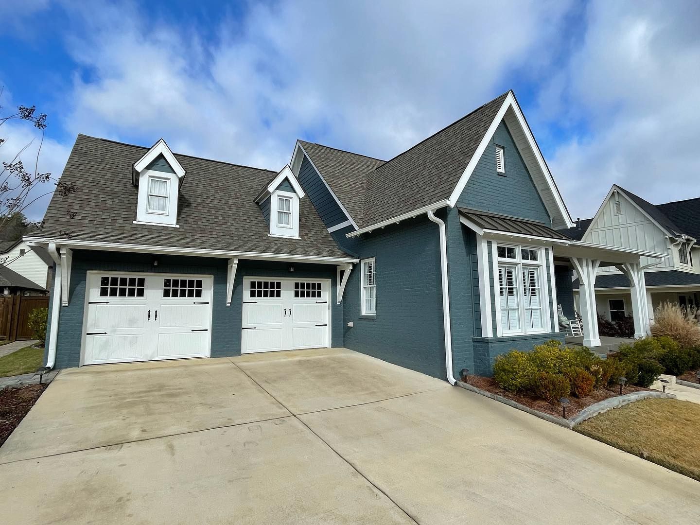 A blue house with white garage doors and a gray roof