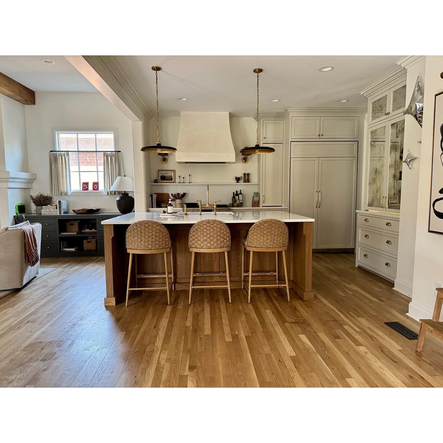 A kitchen with a large island and wicker bar stools.