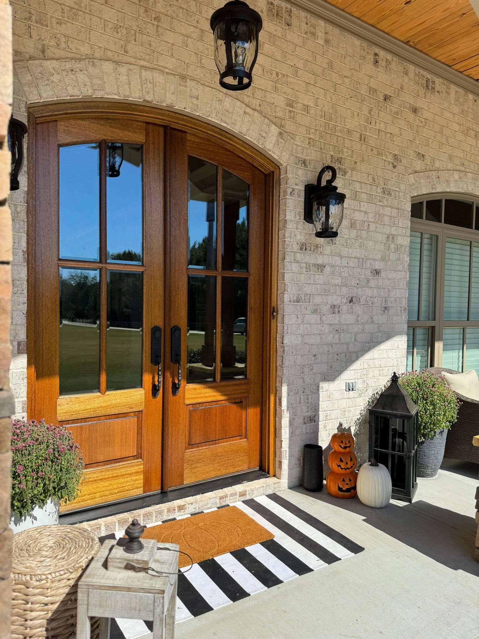 A front porch with a wooden door and a black and white striped rug.