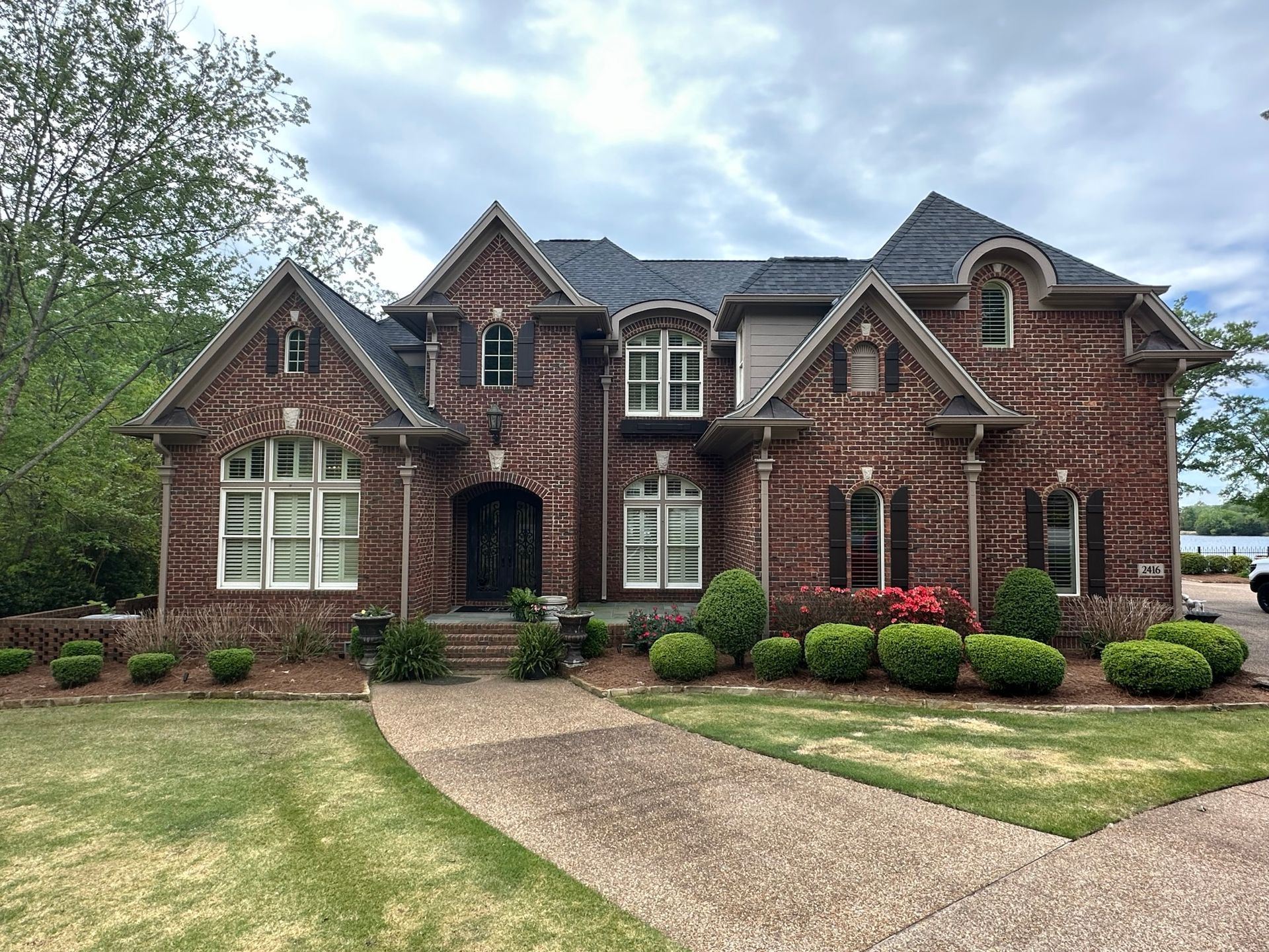 A large brick house with a lot of windows and bushes in front of it.
