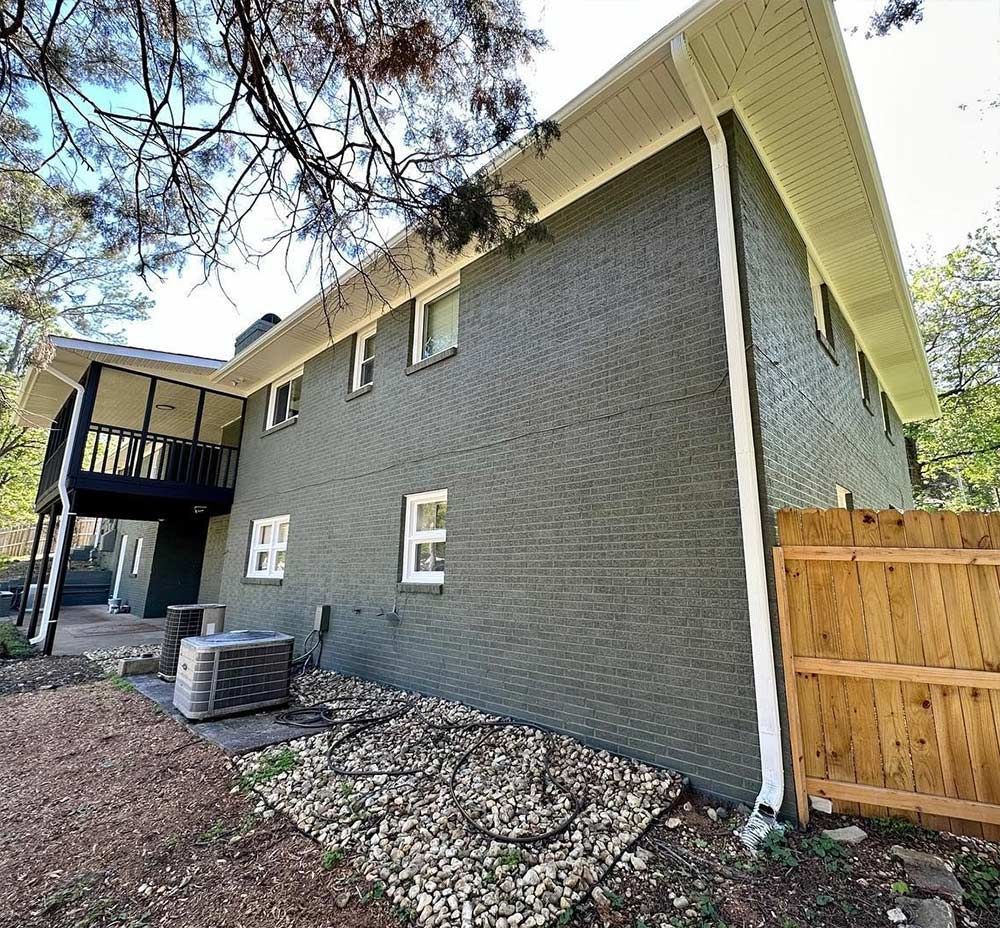 A large brick house with a wooden fence in front of it.