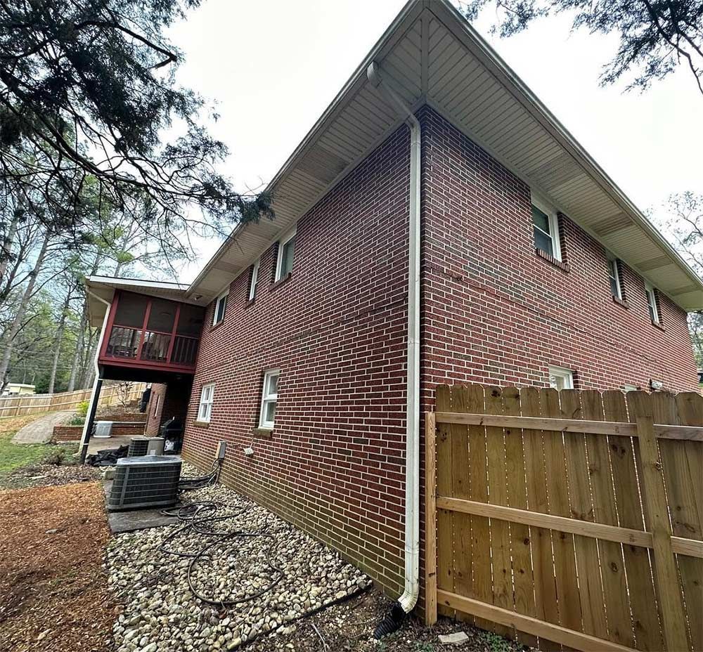 A brick house with a wooden fence in front of it.