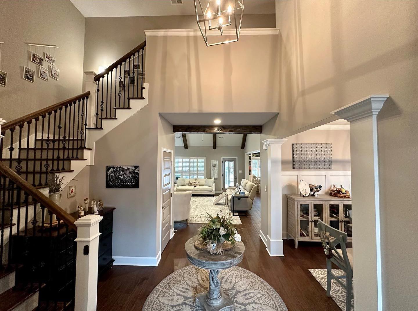 A living room with stairs and a table in the middle