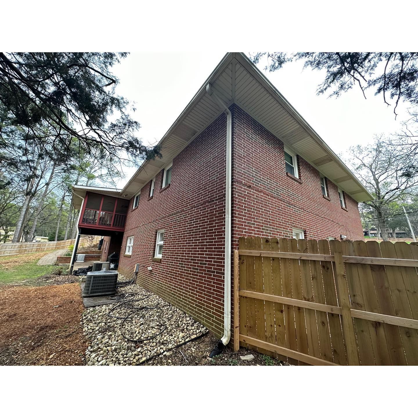 A red brick house with a wooden fence in front of it.