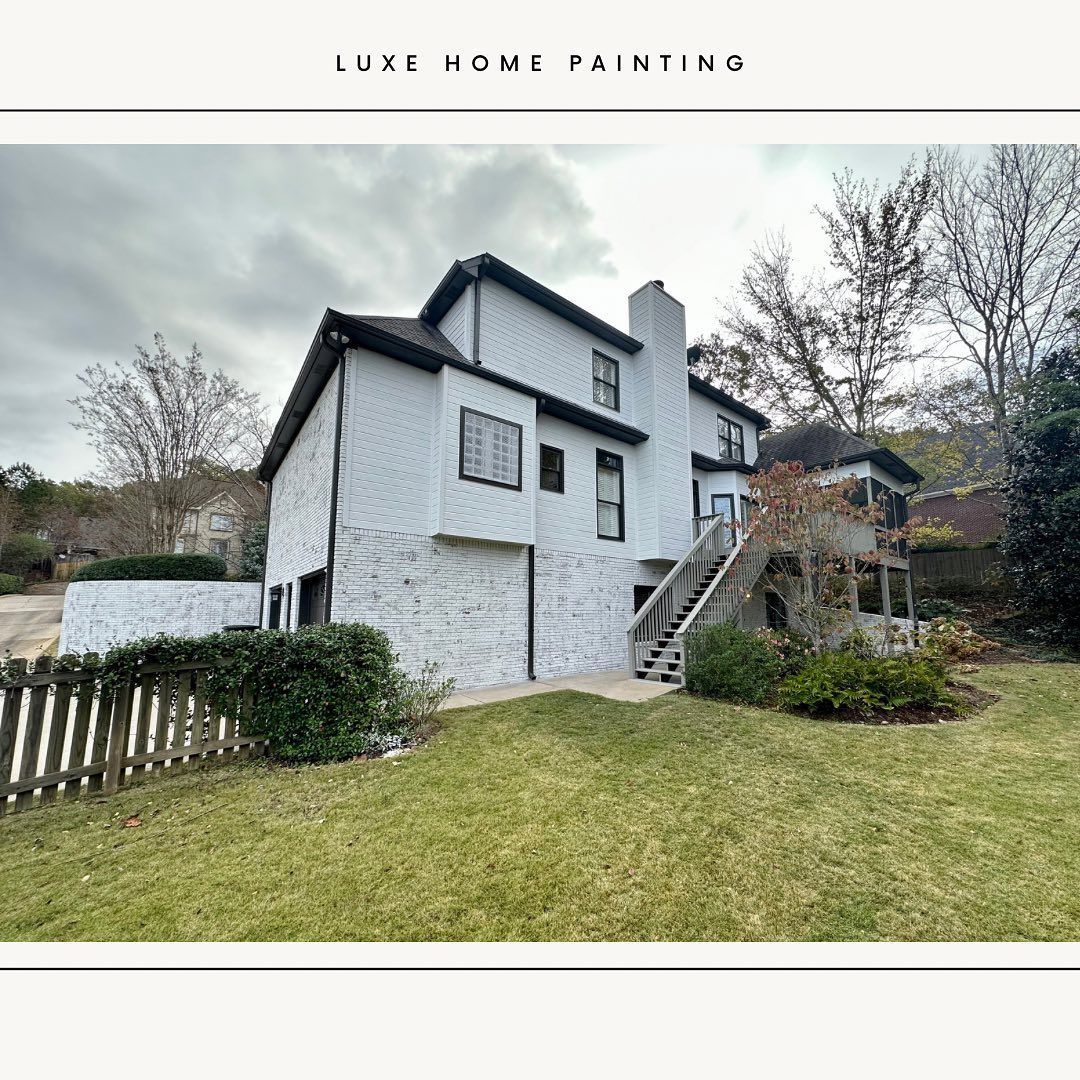 A large white house with stairs leading up to it is sitting on top of a lush green hillside.