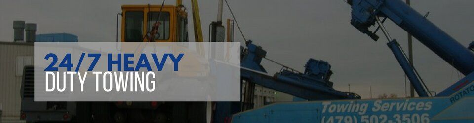 24/7 heavy duty towing service advertisement with blue and white text over a blurred image of a tow truck.