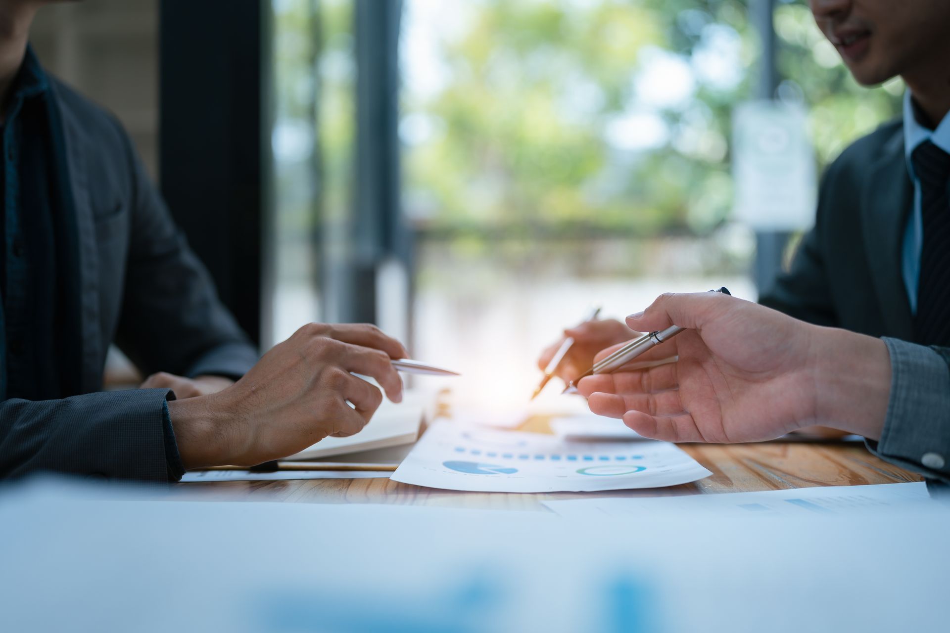 Two men are sitting at a table looking at a piece of paper.