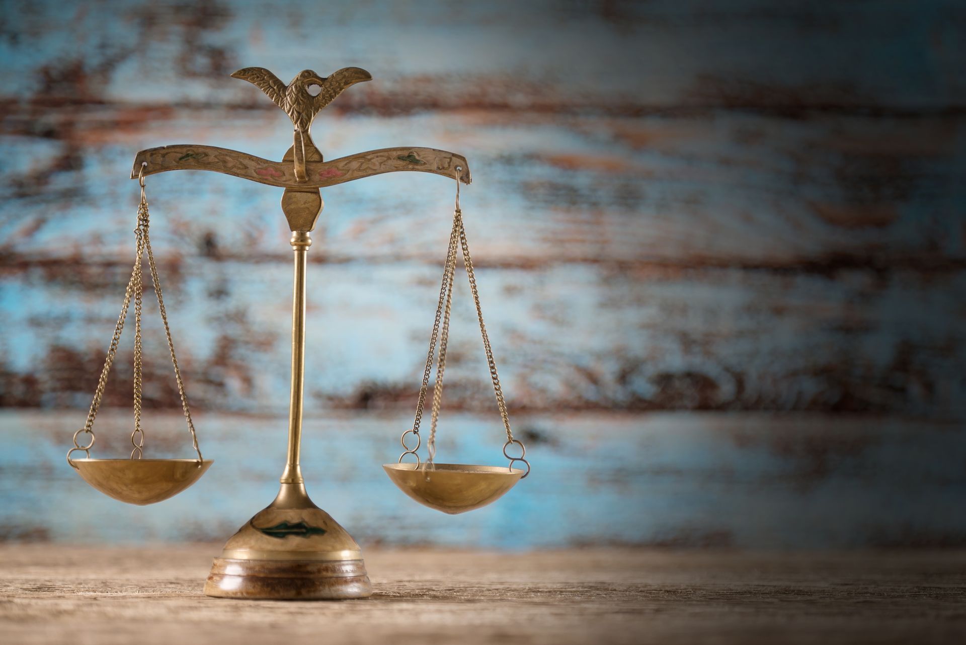 A scale of justice is sitting on a wooden table.