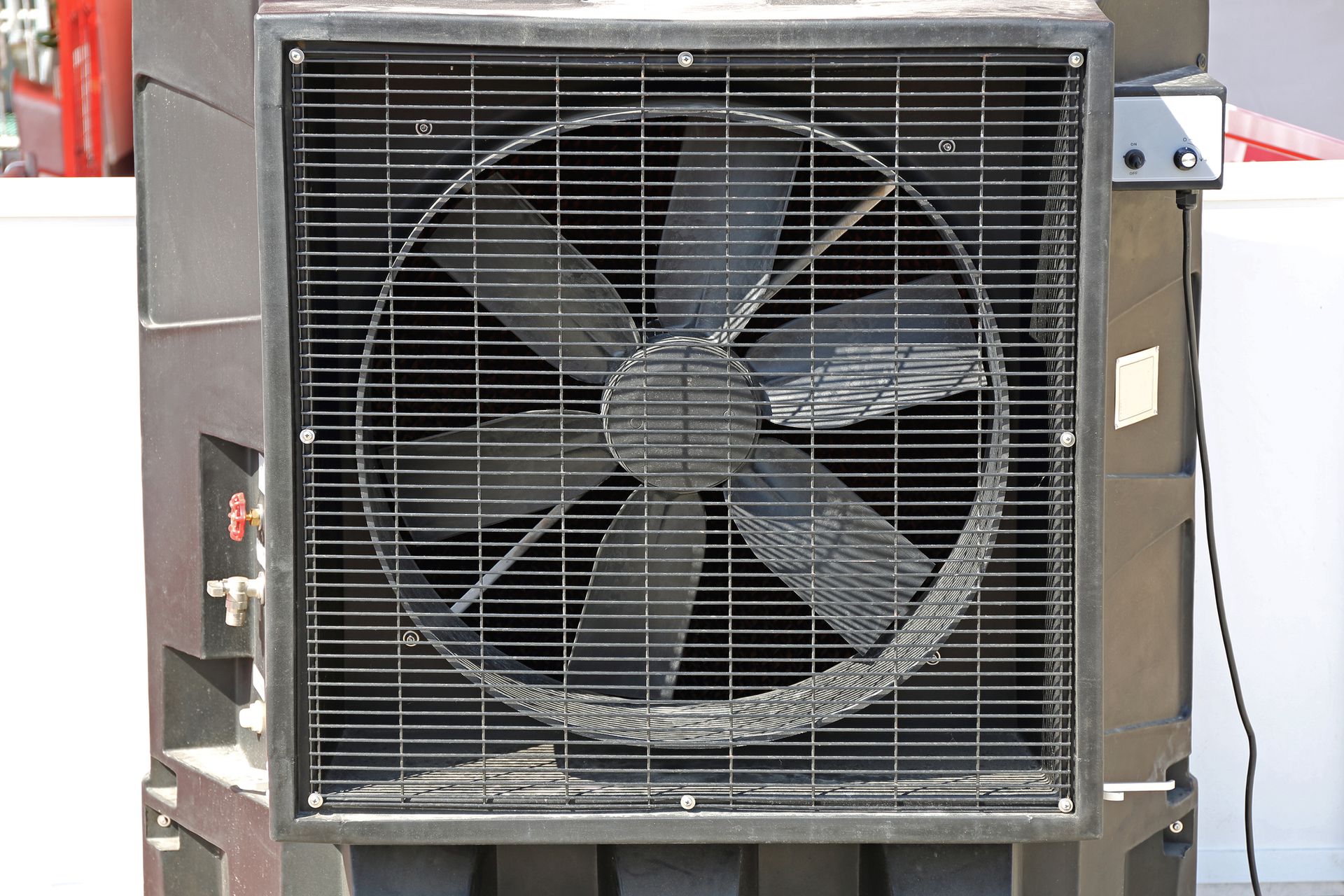 Black industrial evaporative cooler with a large fan behind a protective grill.