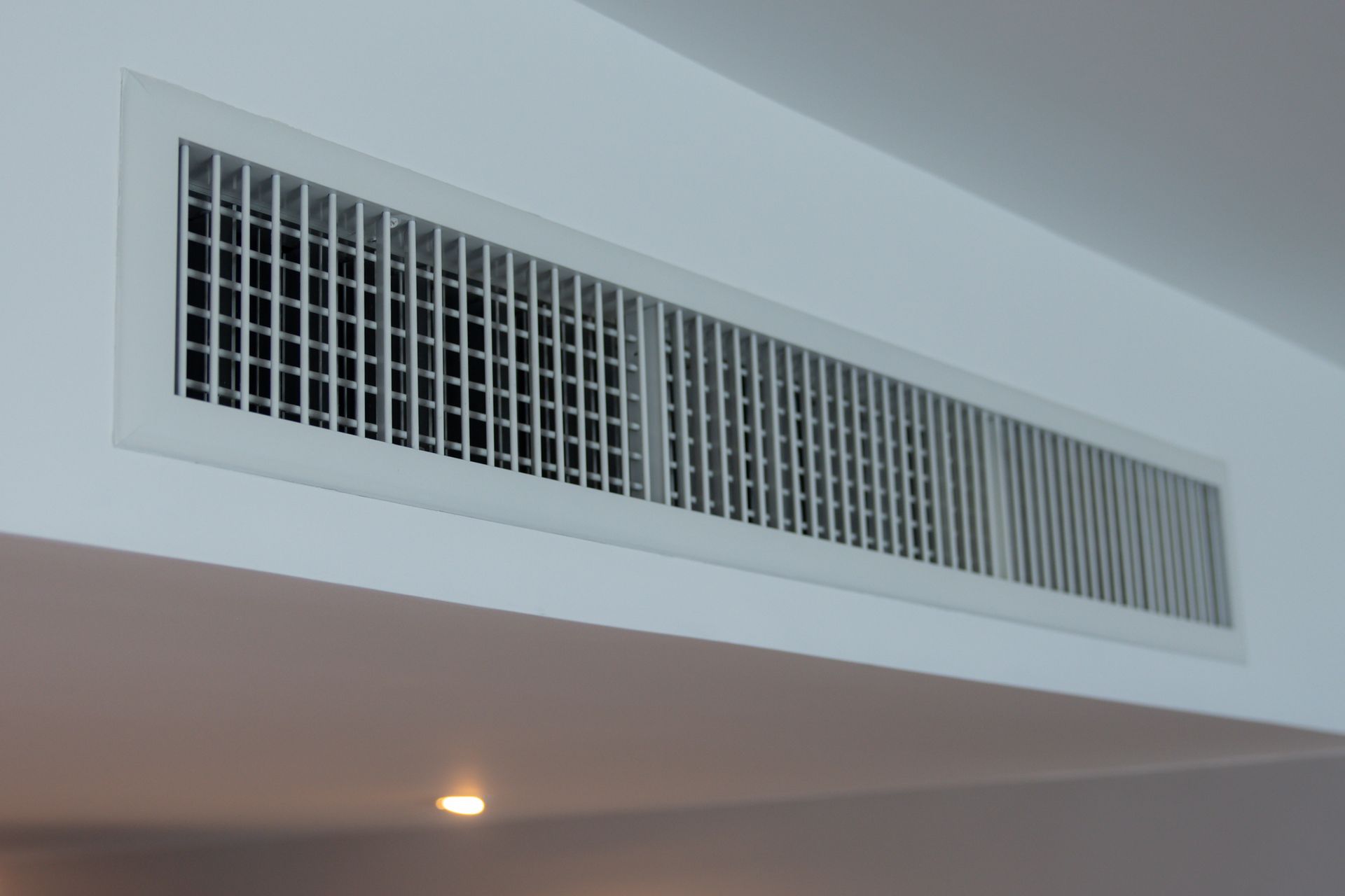 White ceiling-mounted air vent with rectangular grid pattern.