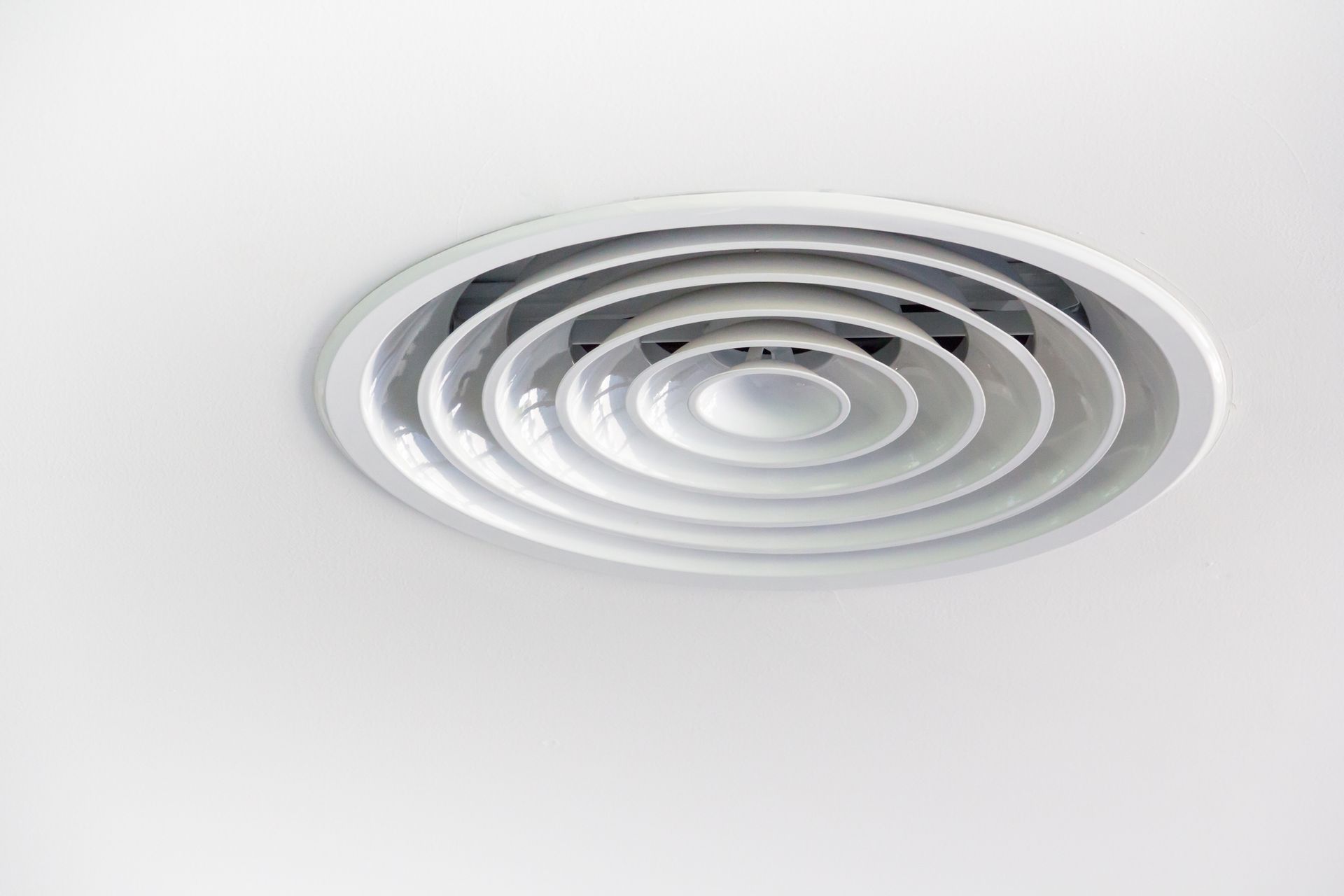 White ceiling air vent with concentric circular baffles.
