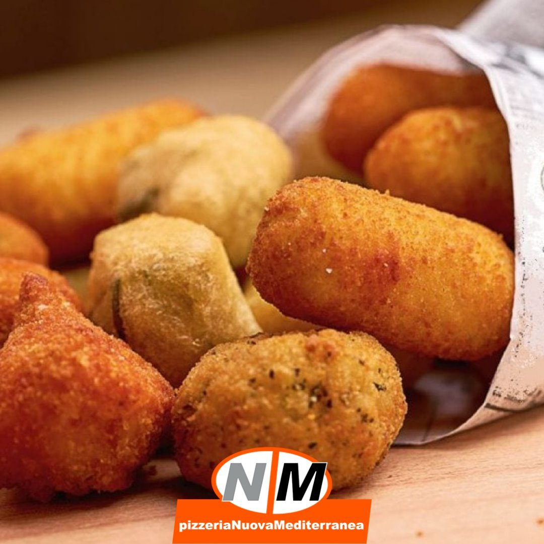 Crocchette fritte assortite, dorate e croccanti, servite in un cono di carta su un piatto di legno.