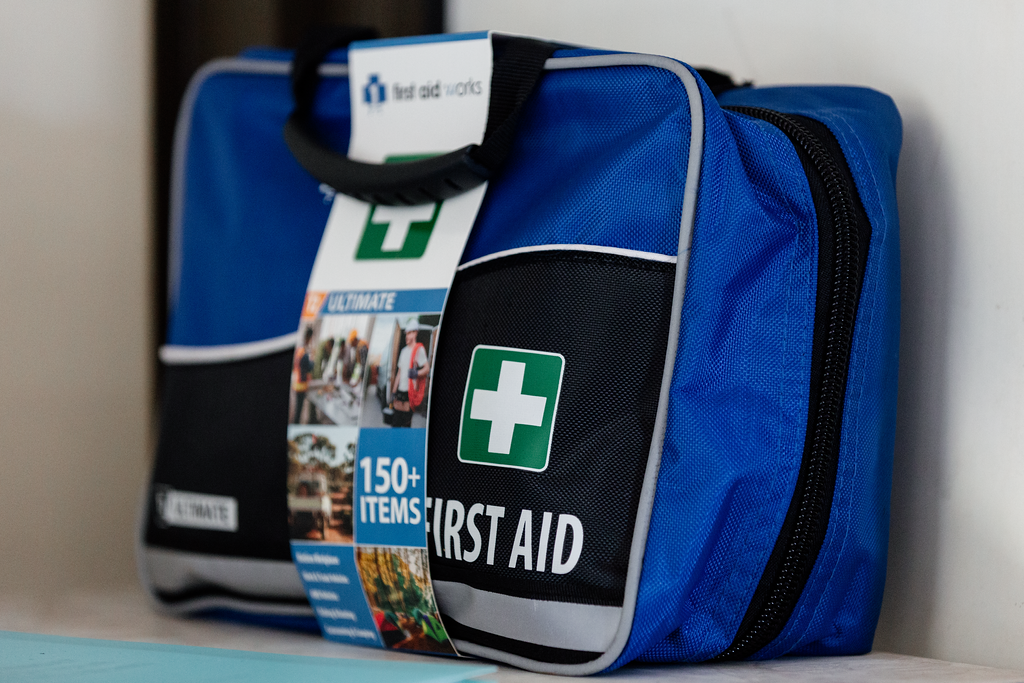 Blue and black first aid kit with white and green medical cross logo;