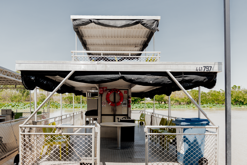 A boat on a calm river reflects the surrounding trees and the sky at dusk.