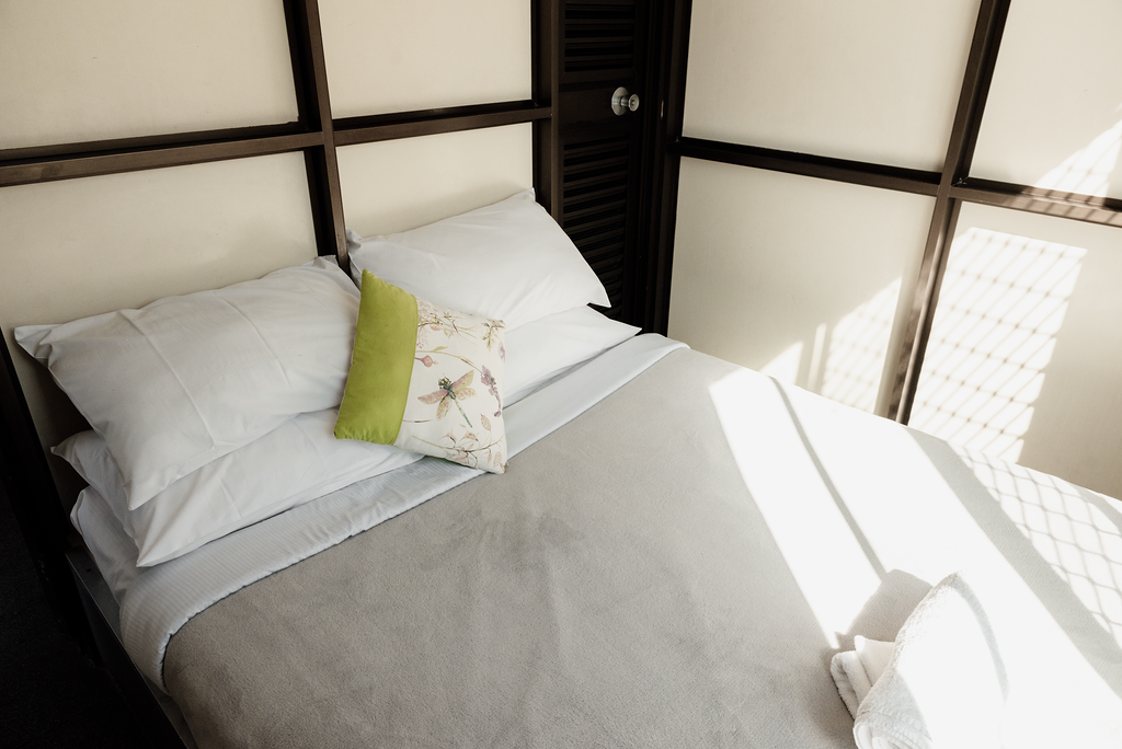Bed in a room with a grid-style wall, white bedding, and a decorative pillow.