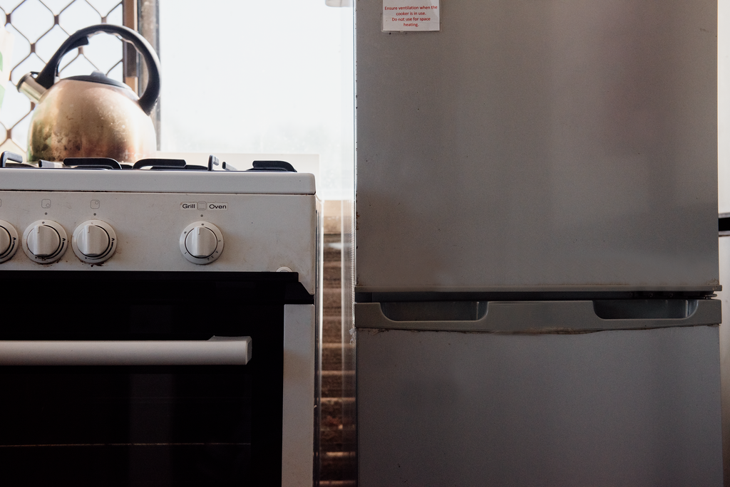 White stove with kettle, and a silver refrigerator in a kitchen.