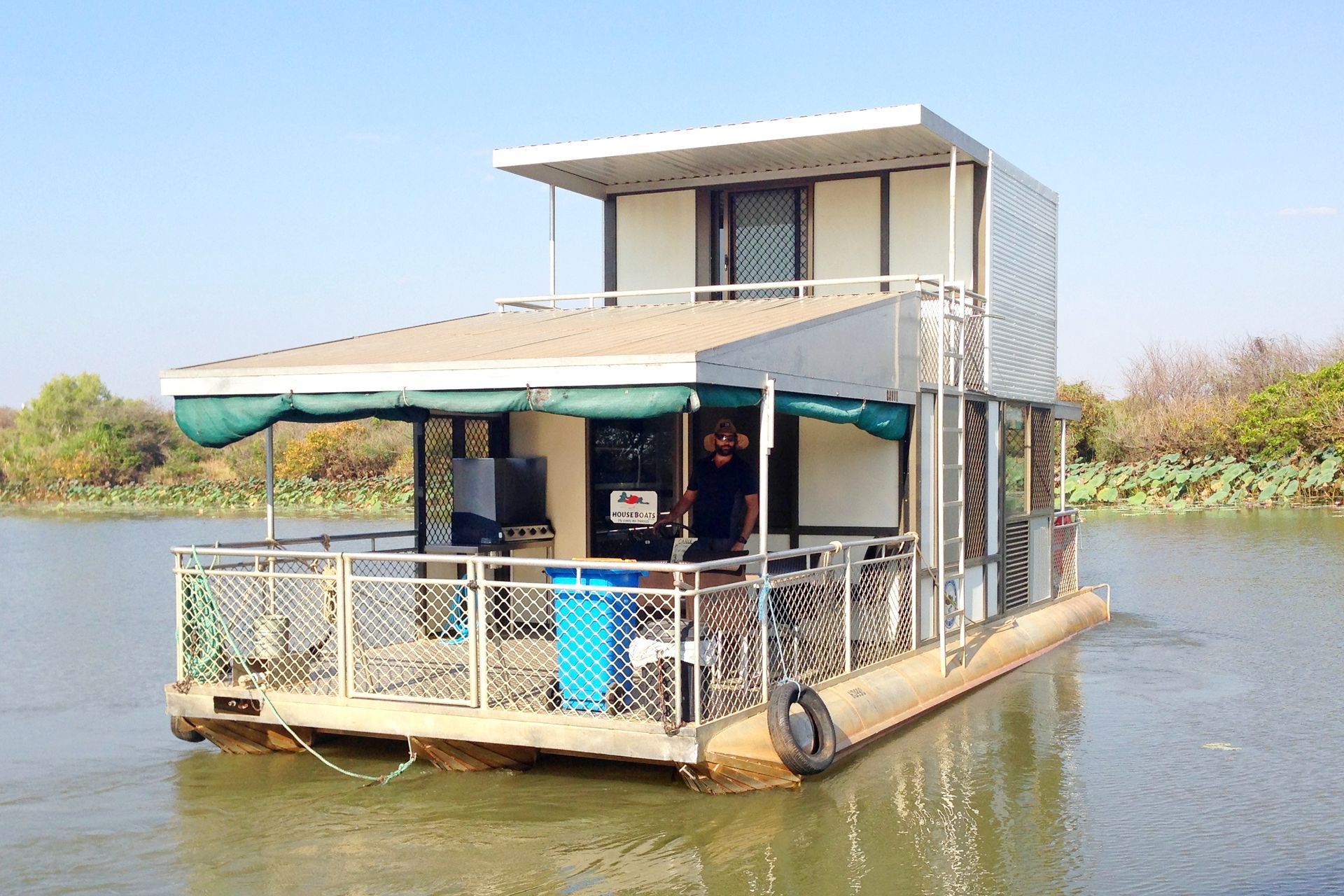 Houseboat cruising on calm water, reflected sky, moon visible.