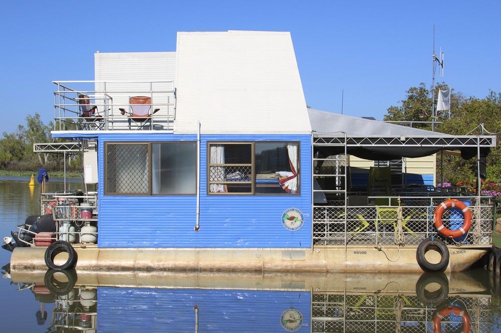 Blue and white houseboat with a deck, floating on water.