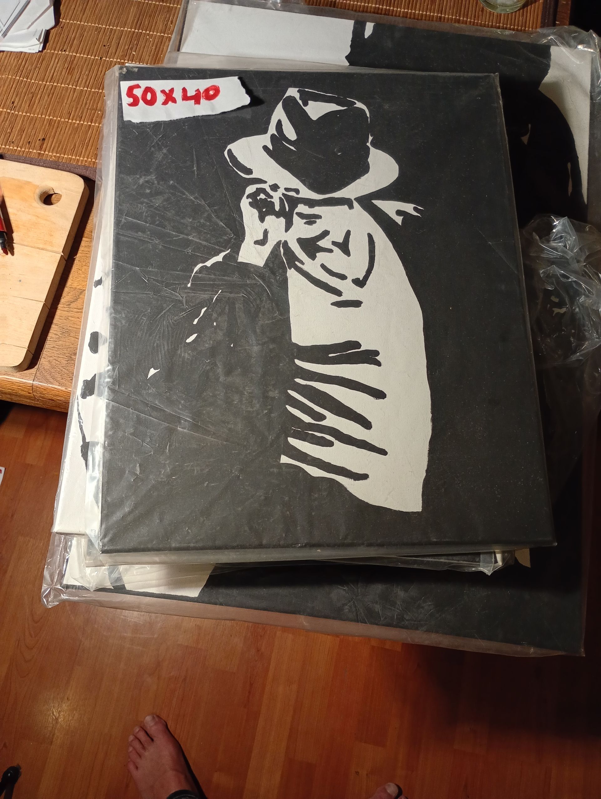 Zwart-wit stencilkunst van een persoon met een hoed en een telefoon, mogelijk Michael Jackson.