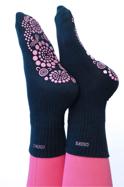 Pilates pose of pink and black crew style grip socks