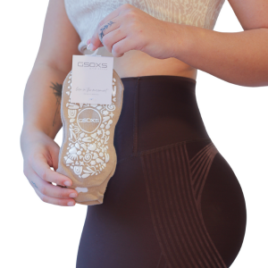 A woman is holding a pair of  GSOXS Pilates grip socks