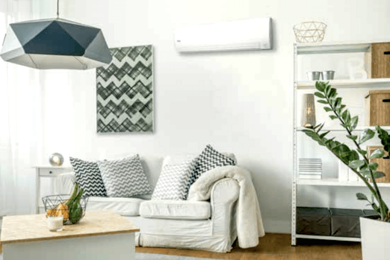 A residental HVAC installed on a wall in the living room on top of the sofa  with a white-and-green motif