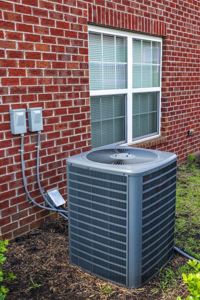 Picture of air conditioner outside next to a red brick wall.