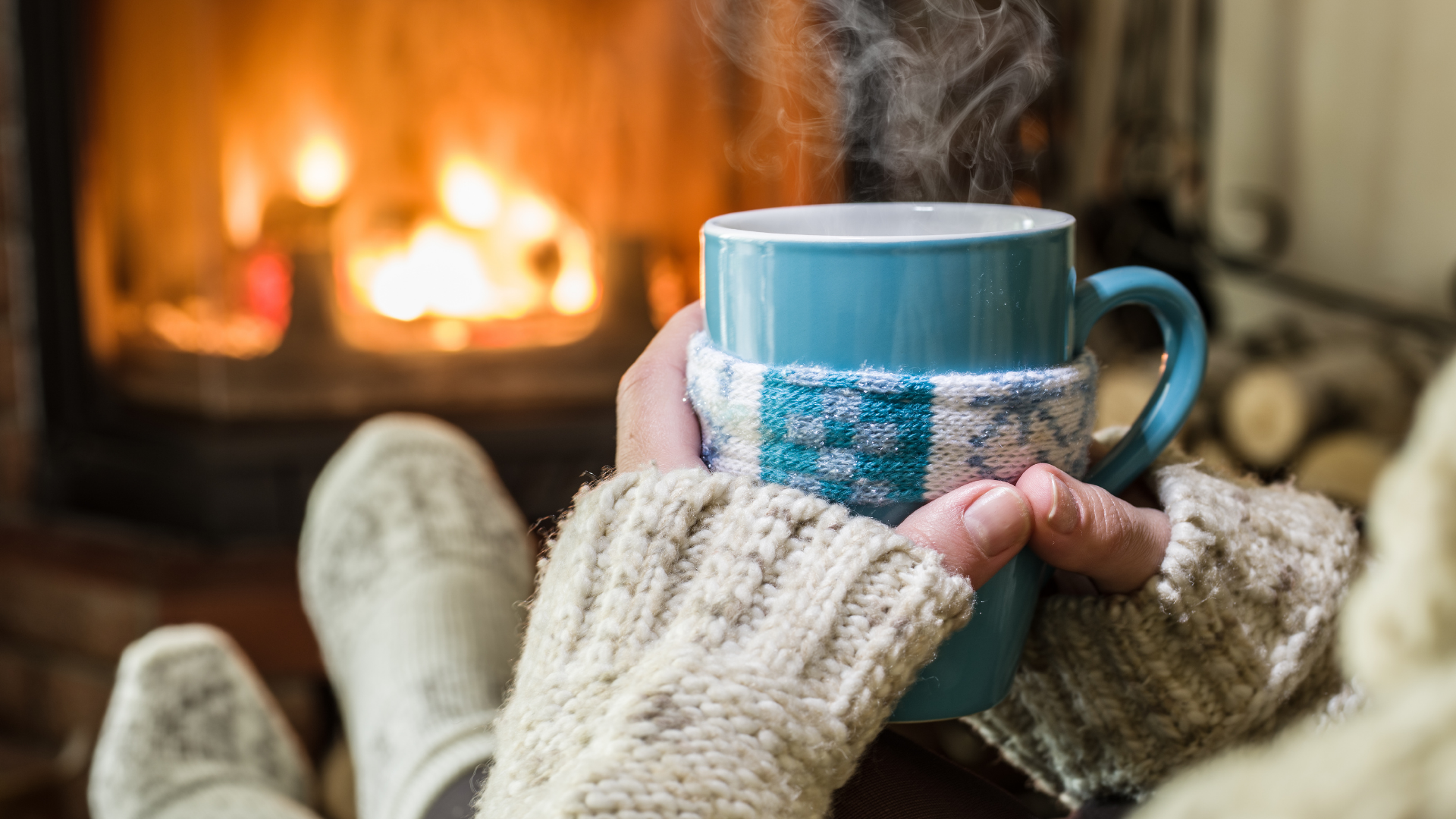 Picture of someone sitting by a fireplace, holding a mug.
