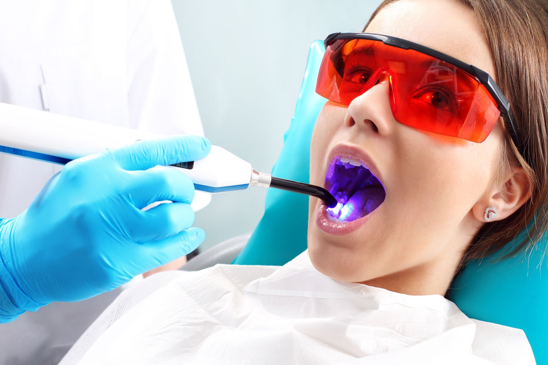 A woman is getting her teeth whitened by a dentist.