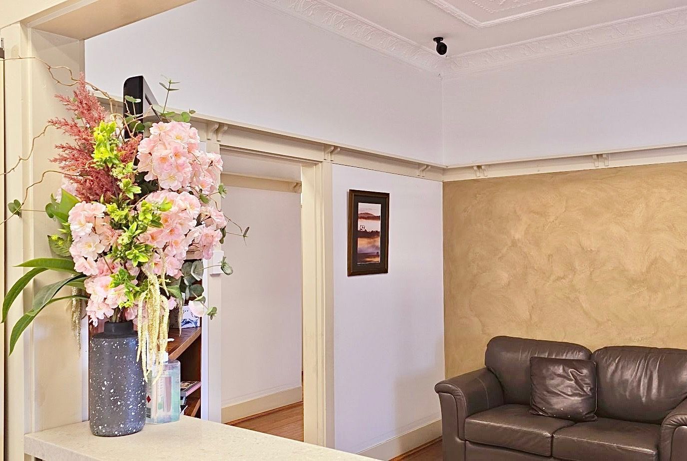 A living room with a couch and a vase of flowers on the counter.