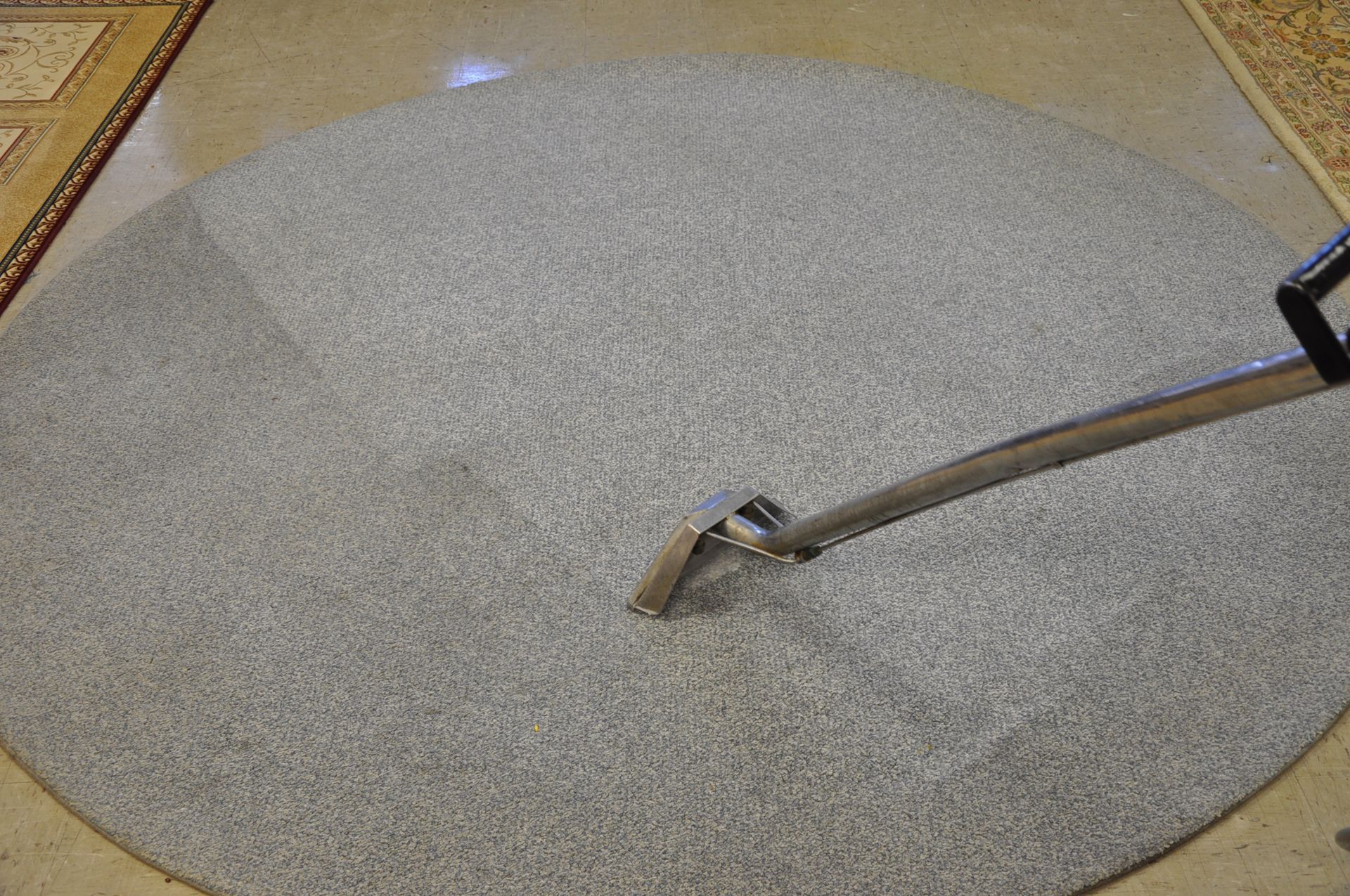 A vacuum cleaner is cleaning a round carpet.