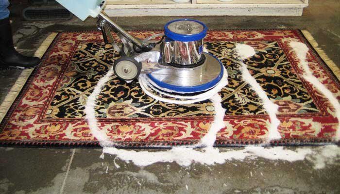 A person is cleaning a rug with a machine