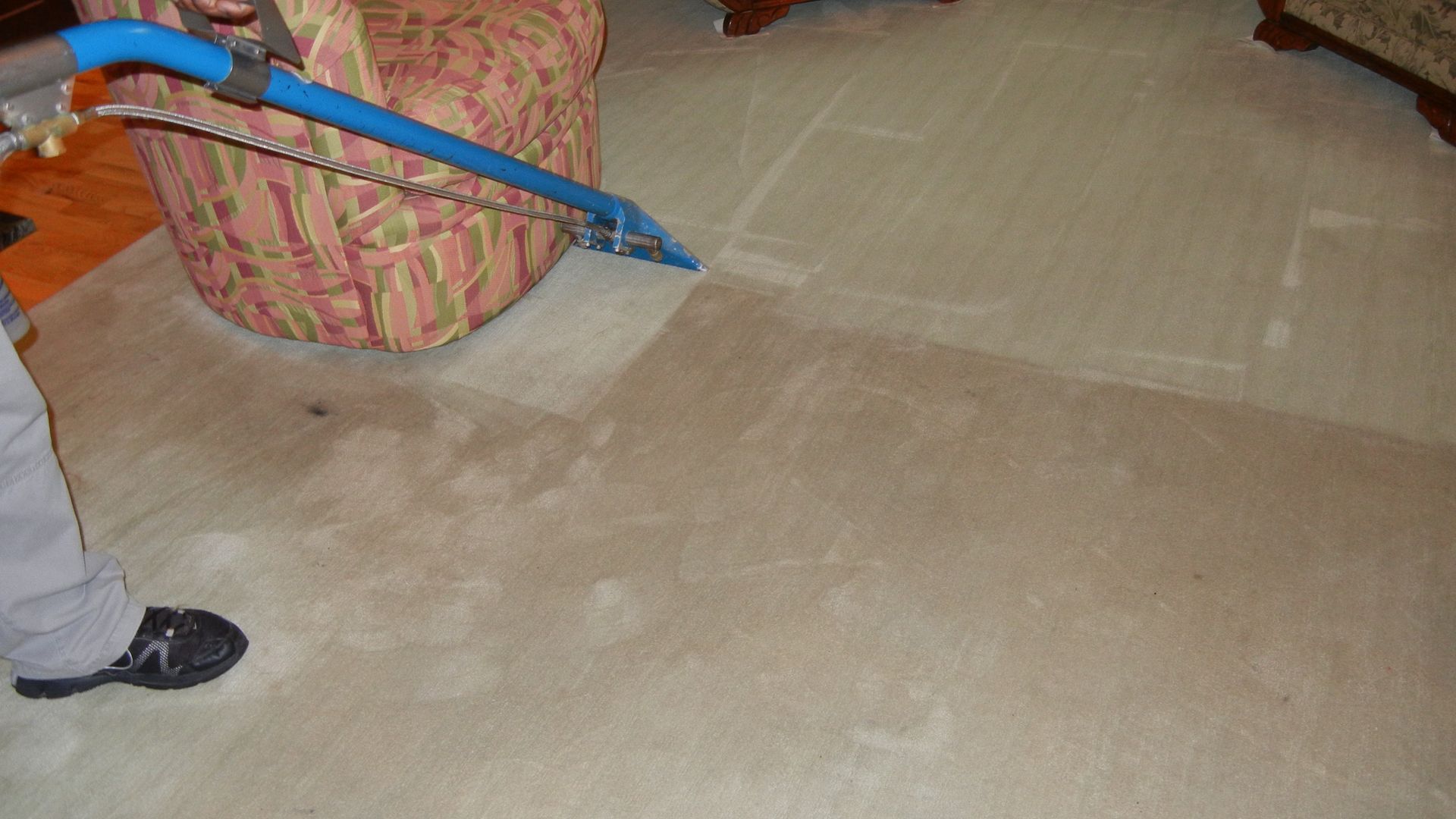 A person is cleaning a carpet with a vacuum cleaner in a living room.