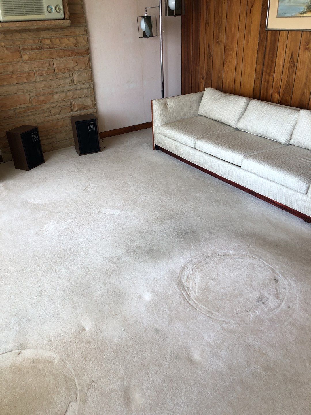 A living room with a white couch and speakers