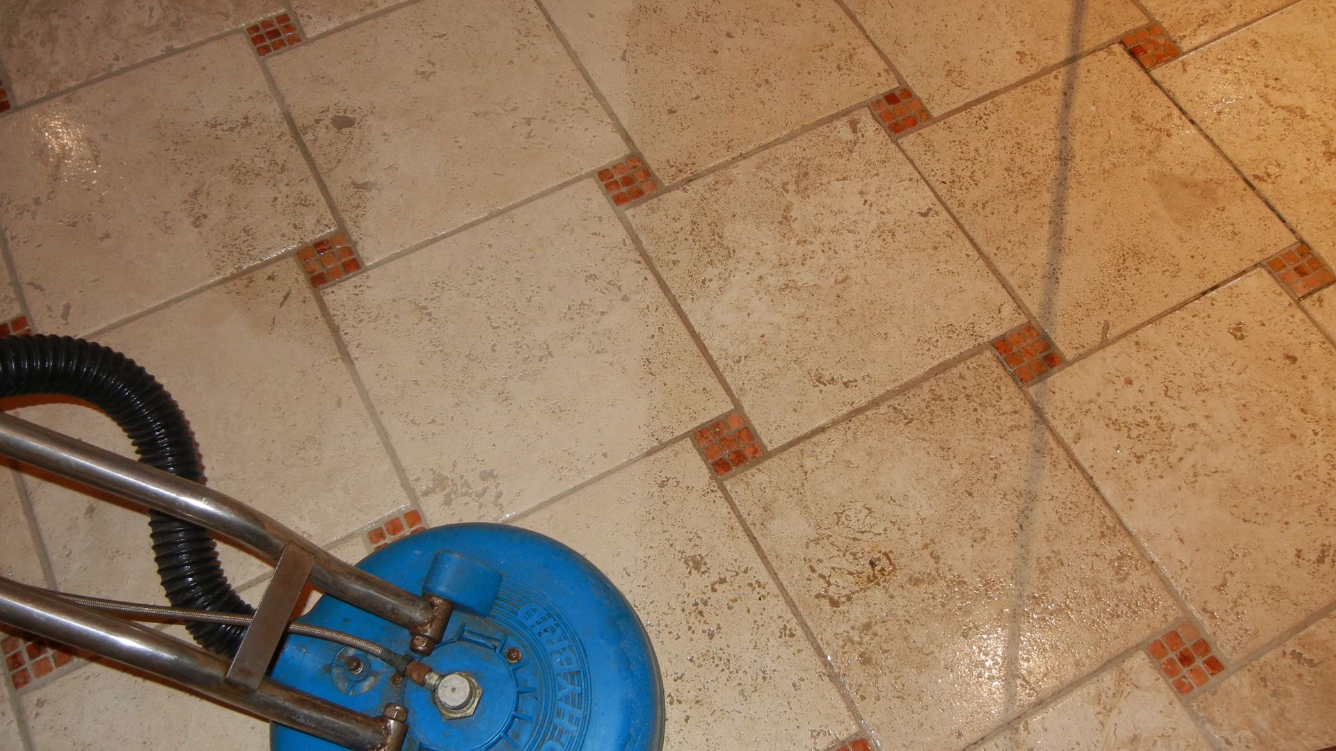 A tile floor is being cleaned with a vacuum cleaner.