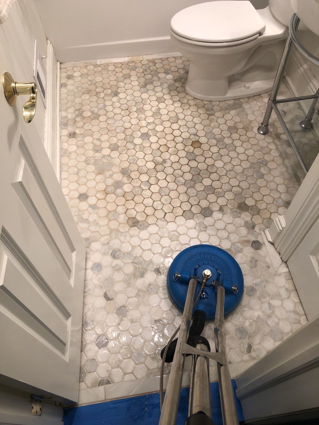 A bathroom with a toilet and a cleaning machine on the floor.