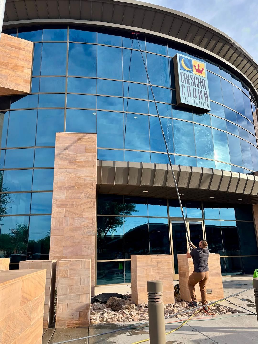 A worker uses a long extension pole to wash the glass exterior of the Crescent Crown Distributing.