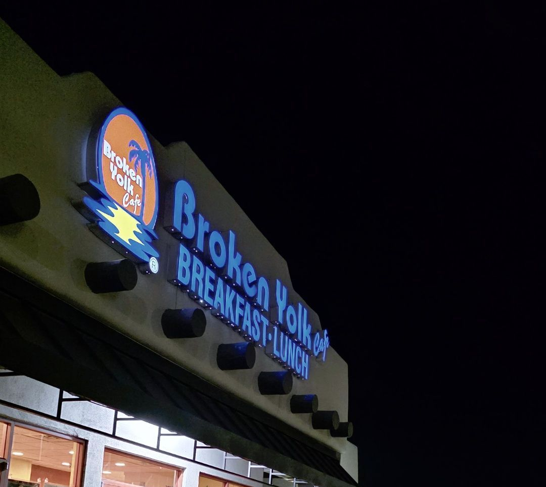 Broken Yolk Breakfast sign glowing blue and orange on a storefront at night