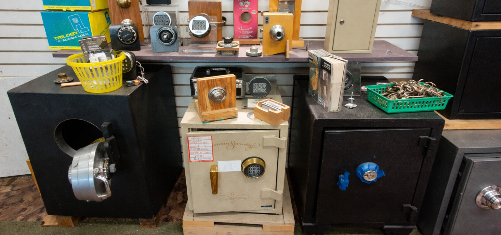 A display of various safes, locks, and security equipment arranged on shelves and stands in a store.