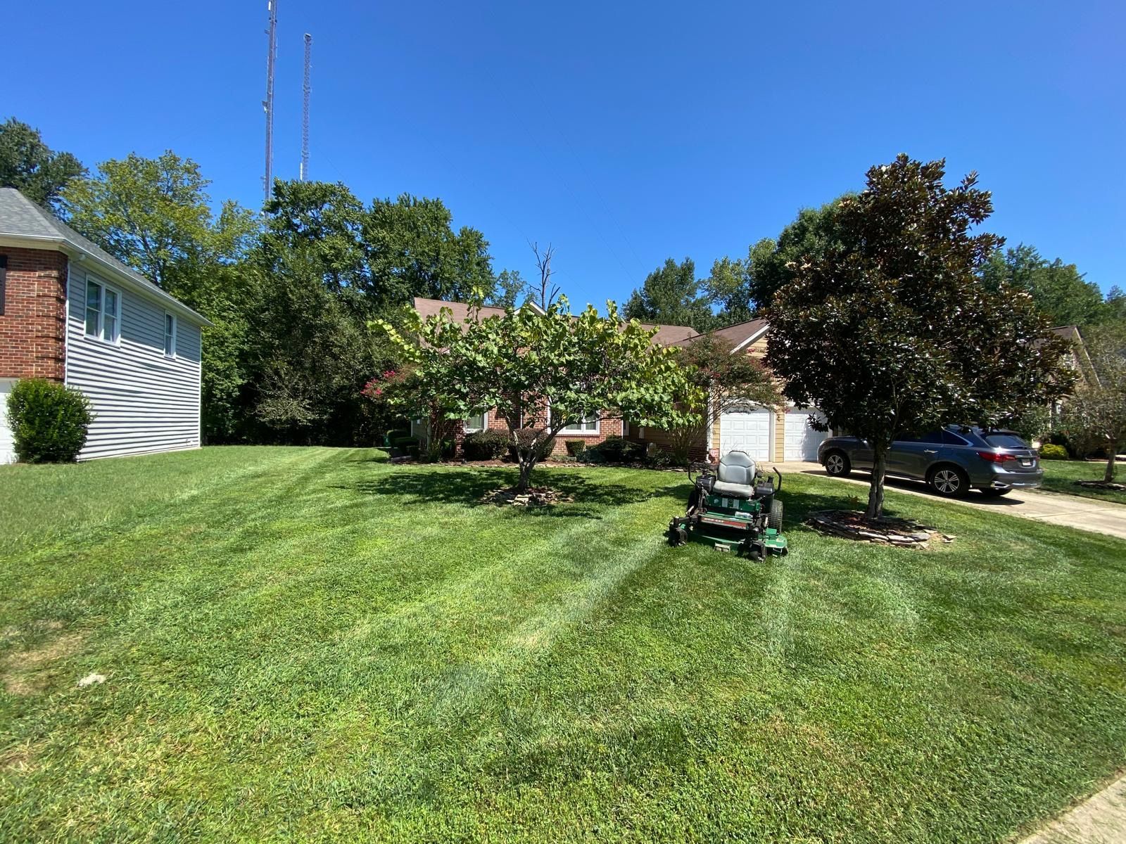 A lawn being mowed in front of a house on a sunny day.