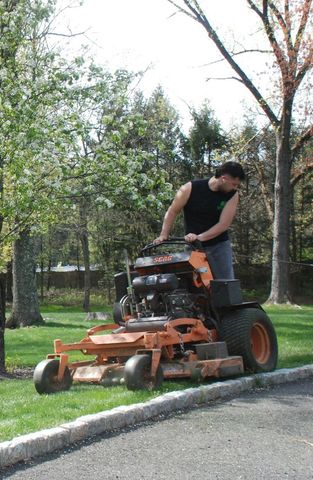 A man is riding a lawn mower on the side of the road.  w/ Collazos