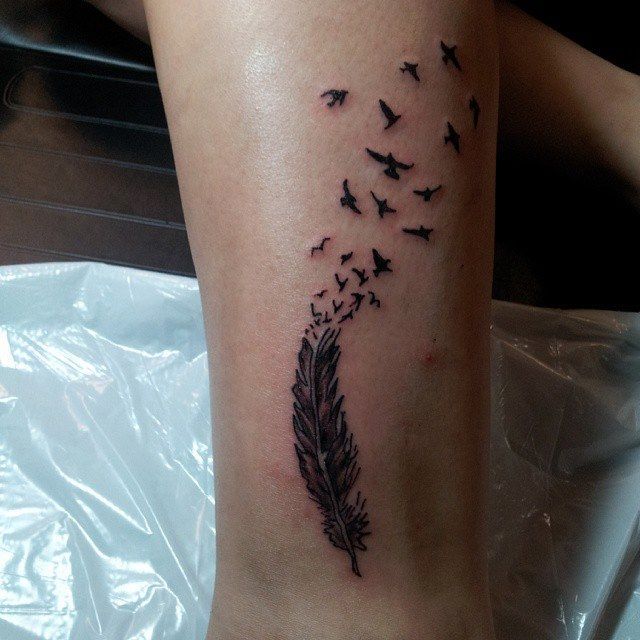 Black feather tattoo with birds flying up.