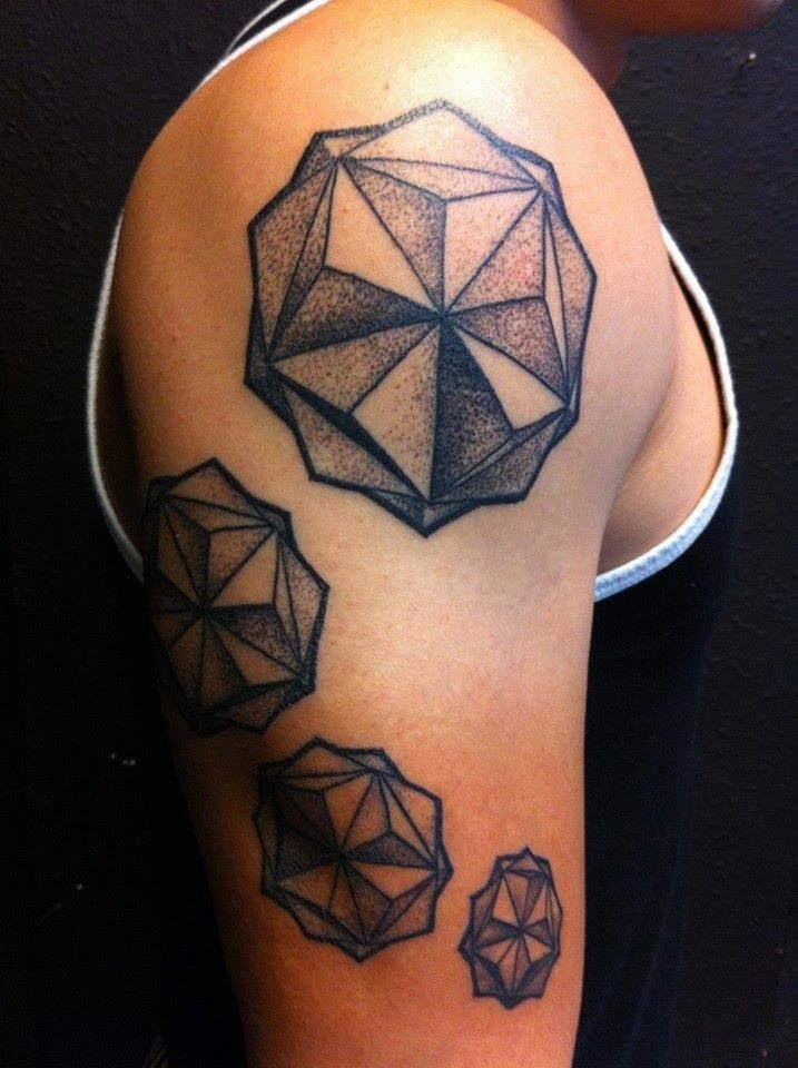 Tattoo of geometric shapes in black ink on a person's upper arm and shoulder.